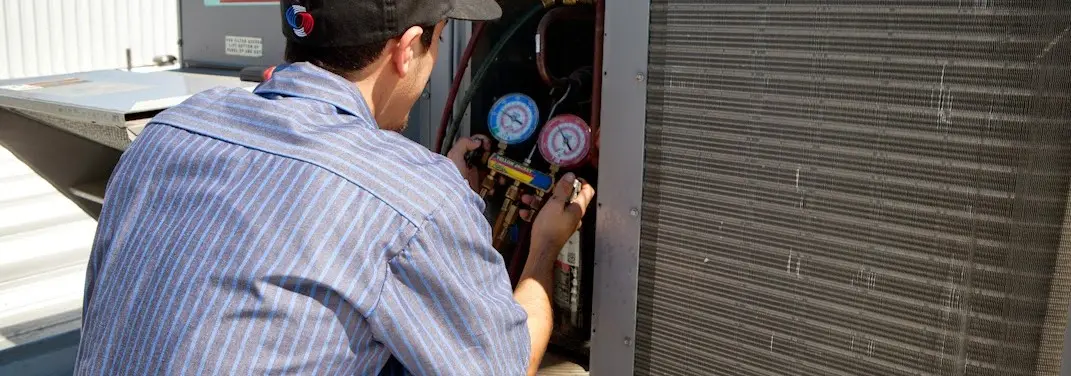 HVAC technician servicing a condenser unit in Salton City